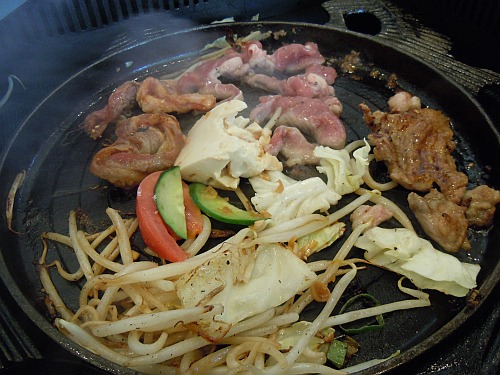 Lamb and vegetables cooking on a Japanese jingisukan griddle.
